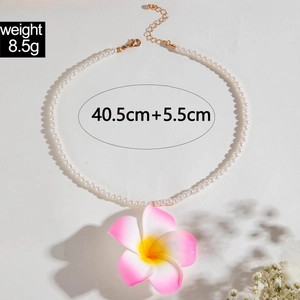 Détail du collier de perles avec un pendentif fleur de frangipanier dégradé rose et jaune