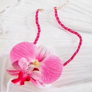 Gros plan sur pendentif orchidée rose avec cordon tressé et accents de perles élégants