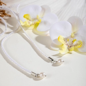 Détail du cordon tressé blanc avec pendentif perle et connecteur en métal argenté