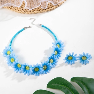 Détail d'un ensemble collier et boucles d'oreilles fleurs bleu clair avec fausses perles