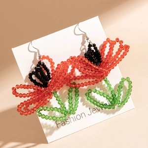 Detail of beaded flower earrings with red petals and green leaves on display card