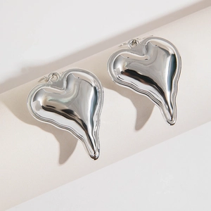Close-up of molten silver heart earrings with a high-shine mirror finish on a minimalist base