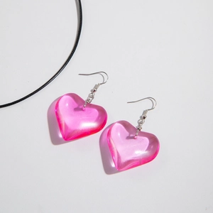 Close-up of translucent pink heart-shaped earrings with glossy resin texture and silver hooks
