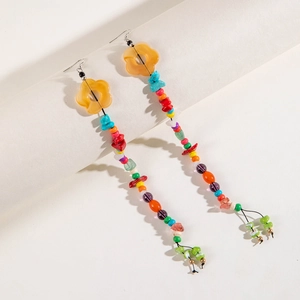 Bohemian colorful beaded tassel earrings with floral accents on a white display stand