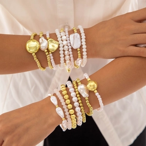Gros plan d'un ensemble de bracelets en perles et perles dorées porté par un mannequin