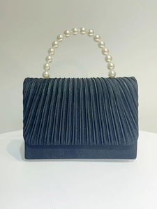 Close-up of pleated black fabric wedding clutch with elegant large faux pearl handle