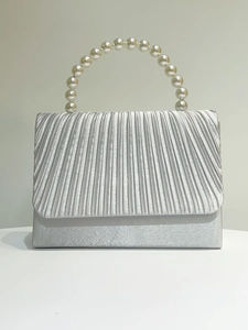 Detail of silver pleated satin evening clutch bag with elegant round pearl handle