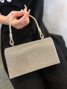 Detailed close-up of a silver evening clutch bag featuring dense sparkling rhinestones
