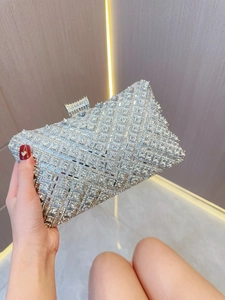 Detail of silver rhinestone evening clutch bag held by hand in luxury setting