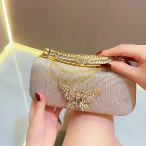 Detail of champagne gold evening bag with a large rhinestone butterfly and encrusted handle