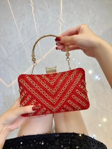 Detailed close-up of red and gold rhinestone evening bag with V-shaped geometric patterns