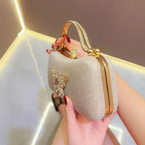 Detail of evening clutch bag featuring a large rhinestone butterfly and gold metal handle