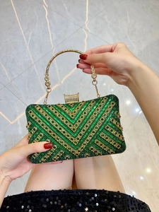 Macro detail of emerald crystal evening clutch with gold handles and V-shaped patterns