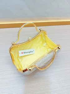 Macro view of crystal evening clutch with gold metal frame and yellow silk lining