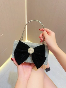 Détail du sac de soirée en strass argenté avec un nœud en velours noir et cristal central