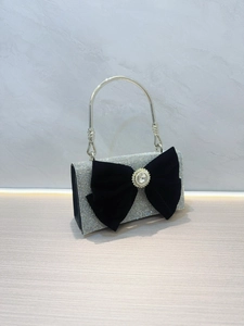 Détail de pochette de luxe sertie de strass argentés avec un grand nœud en velours noir