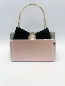 Détail de la pochette de soirée de luxe à strass avec nœud en velours noir et perle