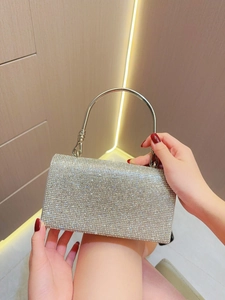 Bolso de noche plateado con pedrería brillante y un asa de metal redondeada