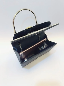 Détail de la pochette de soirée noire avec nœud montrant l'espace pour un smartphone