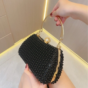 Detail view of black beaded evening clutch bag with gold handle and pearl clasp