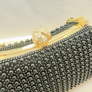 Detail of elegant black beaded evening clutch with gold metal frame and ornate clasp