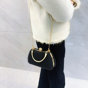 Detailed shot of black beaded evening clutch with gold metal handle and pearl clasp