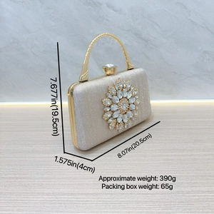 Close-up of champagne evening clutch bag with large rhinestone flower and metal handle