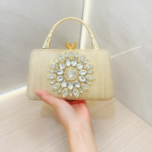 Detail of champagne gold evening bag with rhinestone sunflower and metal handle
