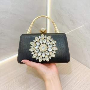 Close-up of a black evening bag with a sunburst rhinestone pattern and gold handle