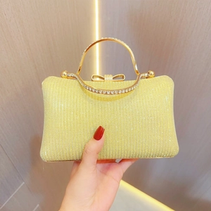 Macro shot of gold rhinestone clutch bag with bow clasp and elegant metal handle