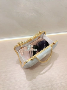 Silver sequin evening clutch bag with gold bow clasp showing internal storage capacity
