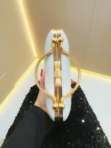 Close-up of silver glitter evening clutch bag with gold round handle and crystal bow clasp