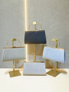 Detailed close-up of pleated evening clutch bags with rhinestones and gold ring handles