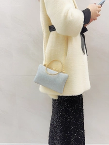 Detail of silver glitter evening bag with gold bow clasp and metallic handle