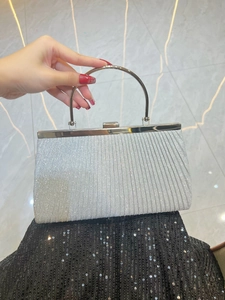 Close-up of pleated silver sequin evening clutch bag with semicircular metal handle