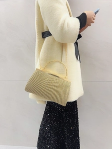 Detail of pleated gold evening clutch bag with round metal handle and chain strap