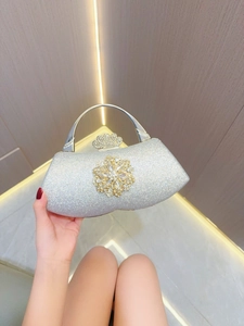Detail of silver sequin evening bag with crystal flower and crown clasp held by hand