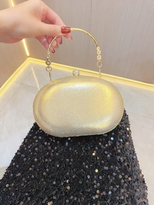 Dettaglio borsa da sera dorata con chiusura a sfera di cristallo e manico ad anello
