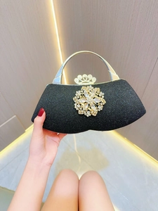 Close-up of elegant black glitter evening bag with large crystal flower and gold handle