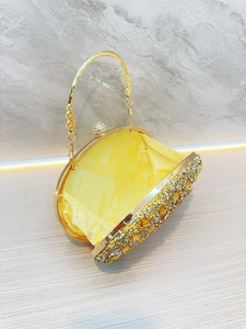 Dettaglio pochette da sera con manico in metallo dorato, strass e fodera in raso giallo