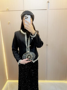 Elegante pochette da sera con paillettes nere e decoro floreale abbinata a una gonna