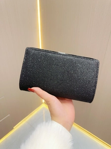 Close-up of black glitter evening clutch bag with metallic lock held by a hand