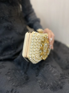 Detailed macro view of a luxury evening clutch featuring rhinestones and a yellow flower jewel