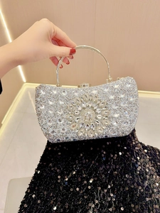 Macro detail of sunflower crystal ornament and silver rhinestones on the evening clutch bag
