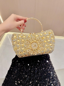 Detail of luxury gold evening bag with rhinestone sunburst pattern and metal handle