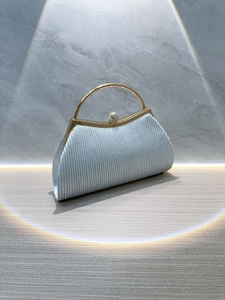 Close-up of pleated silver evening clutch with gold round handle and rhinestone clasp