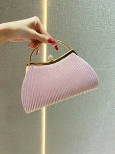 Detail of pink pleated evening clutch with golden ring handle and rhinestone clasp