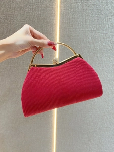 Detailed view of a red pleated evening clutch with golden handle and crystal clasp