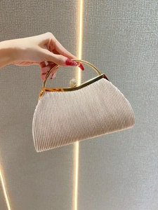 Detail of champagne pleated evening bag with gold handle and sparkling rhinestone clasp