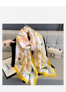 Detailed view of floral silk scarf featuring yellow edges and vibrant botanical prints